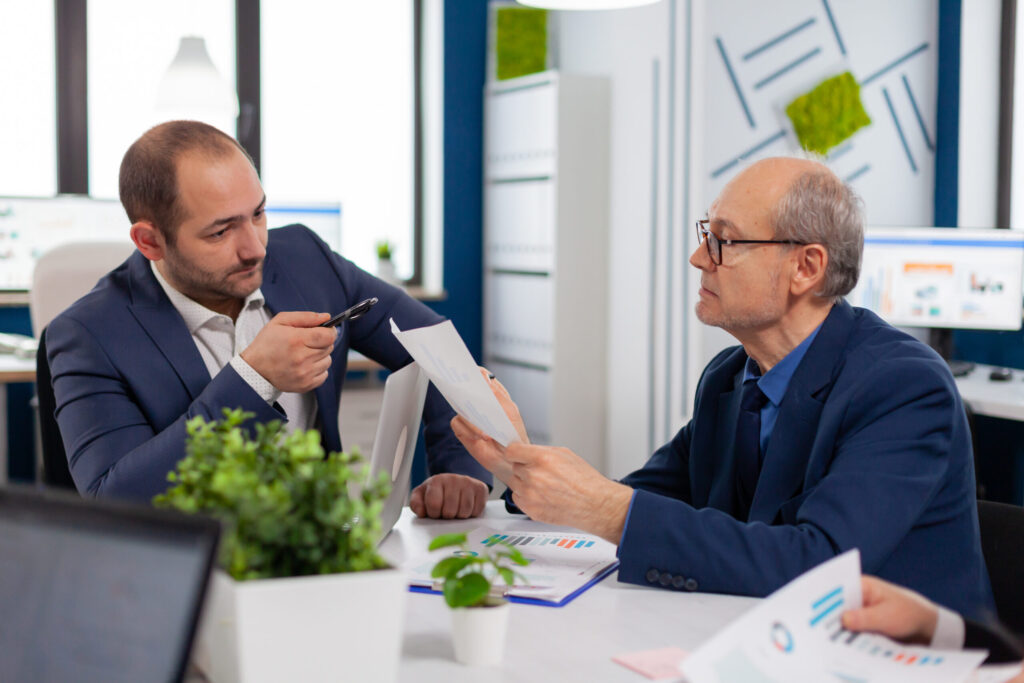 Tax Planning Strategies for Small Businesses in 2026 - Reduce Liability Legally senior entrepreneur discussing with coworker holding documents conference briefing businessman discussing ideas with colleagues about financial strategy new start up company scaled.jpg